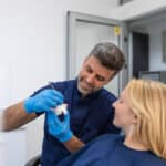 Dentist explaining dental bridge model to female patient